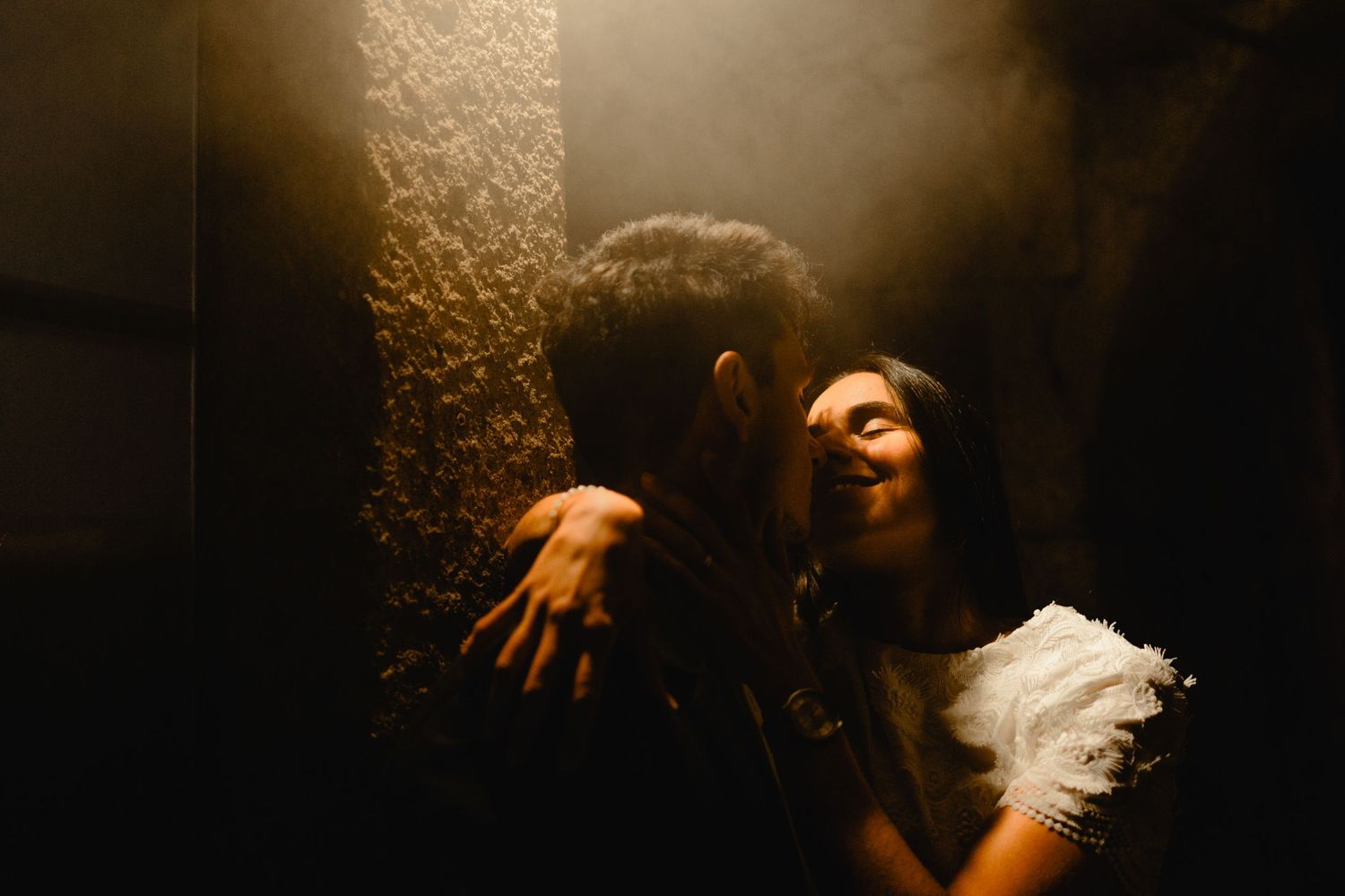 Romantic couple embracing in a dimly lit shower, sharing an intimate moment in warm golden light.