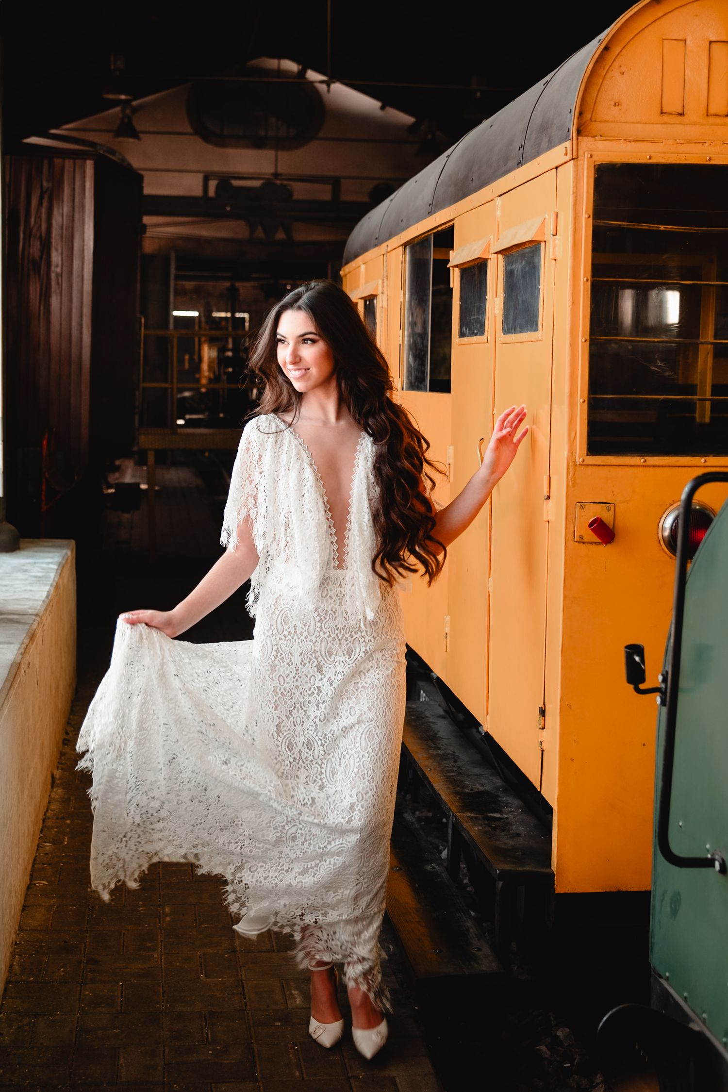 Beautiful lace wedding dress photographed against vintage orange train car.