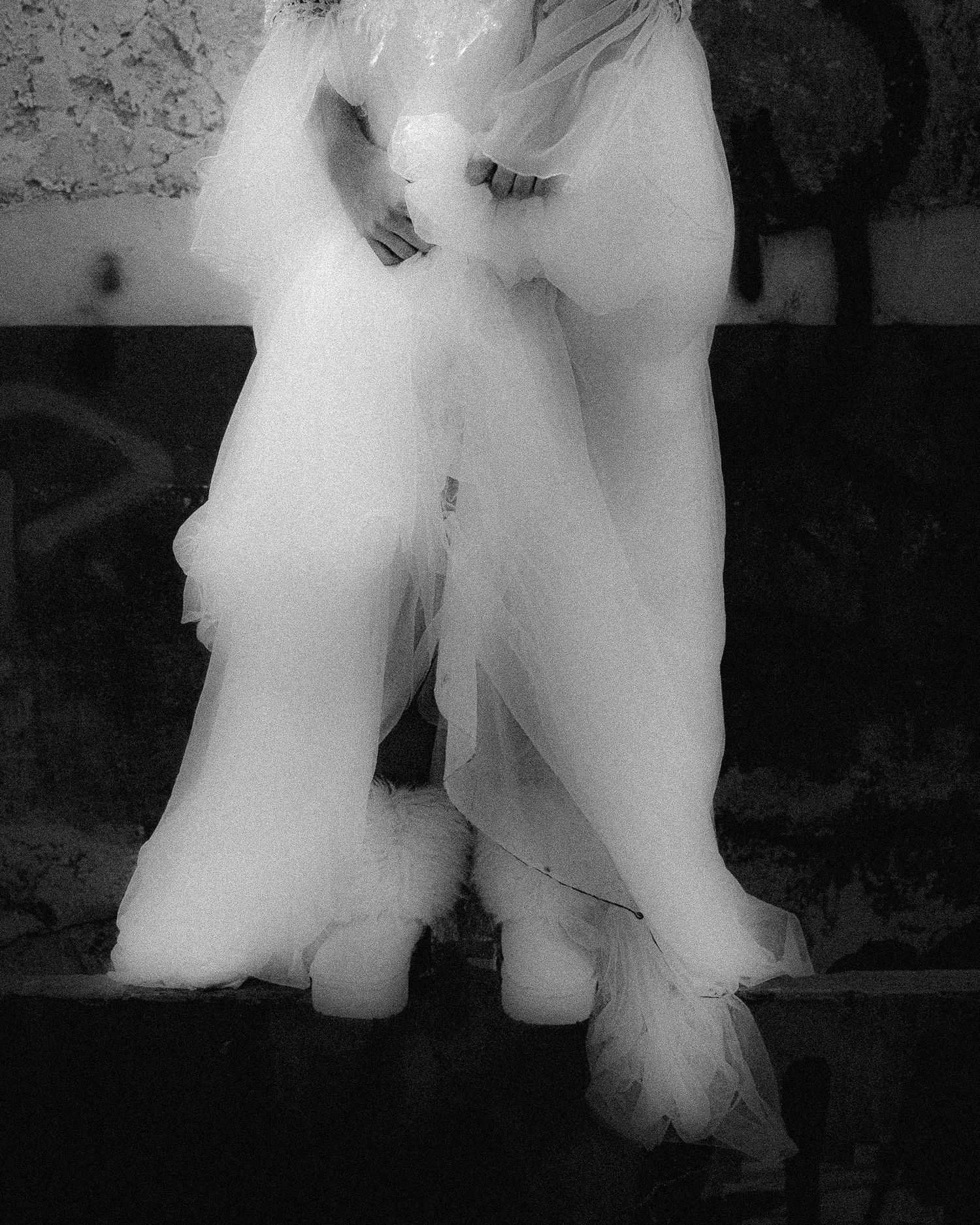 Close-up of flowing white tulle fabric and wedding dress details in black and white.