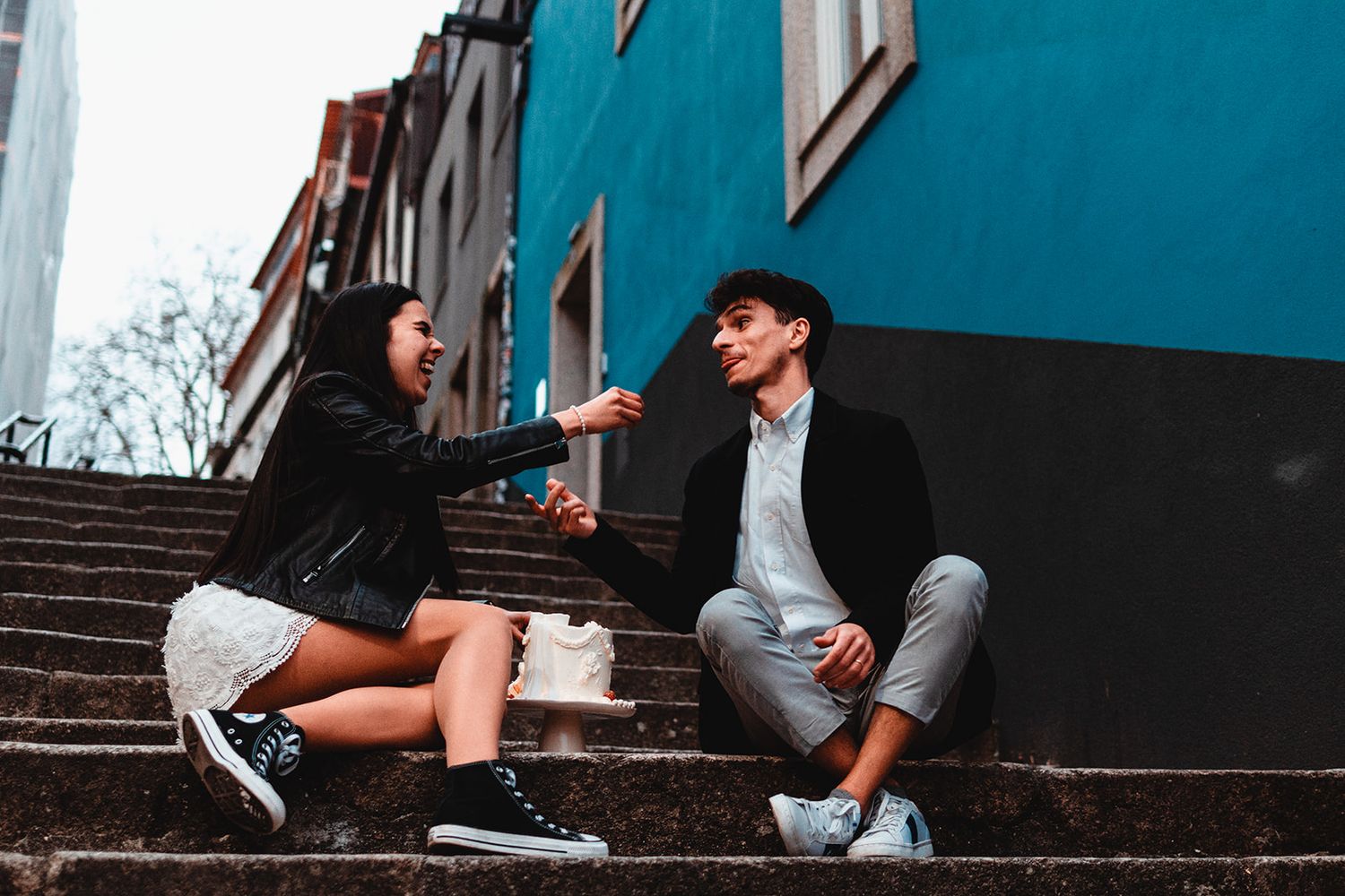 People sitting on blue-walled steps wearing trendy sneakers and casual attire.