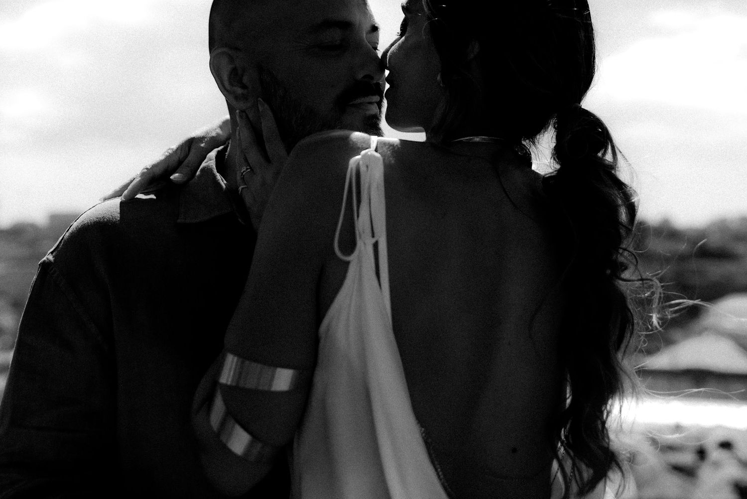 Silhouetted figures sharing an intimate moment against a bright background.