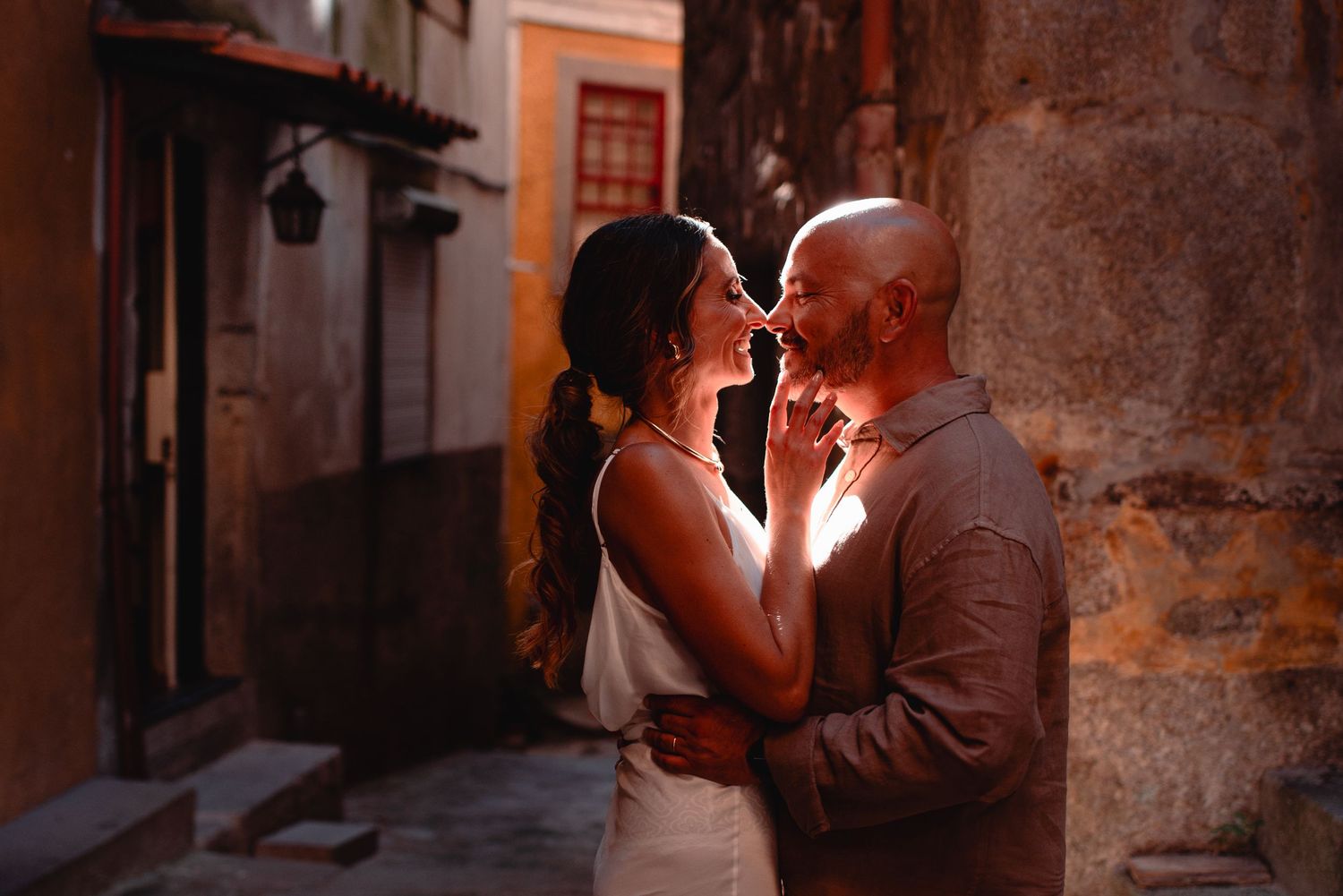 Warm-toned photograph of couple in romantic moment within historic stone alley.