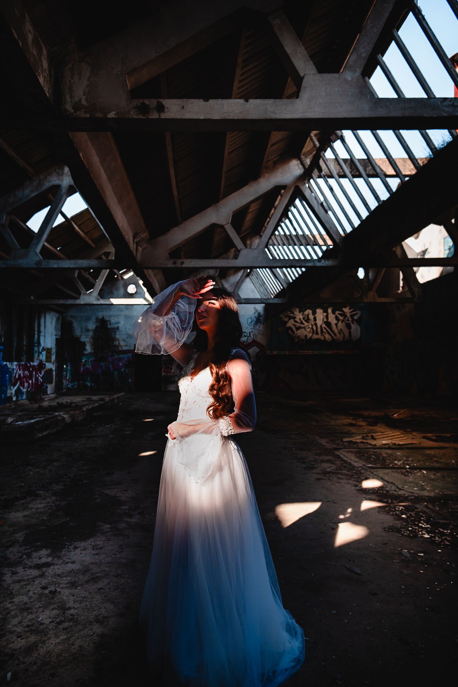 Moody wedding portraits in an abandoned warehouse with dramatic lighting and shadows.
