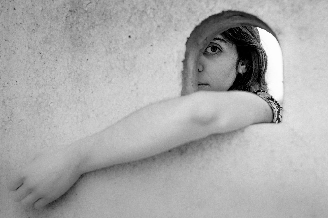 Artistic black and white portrait showing an arm against a stark wall.