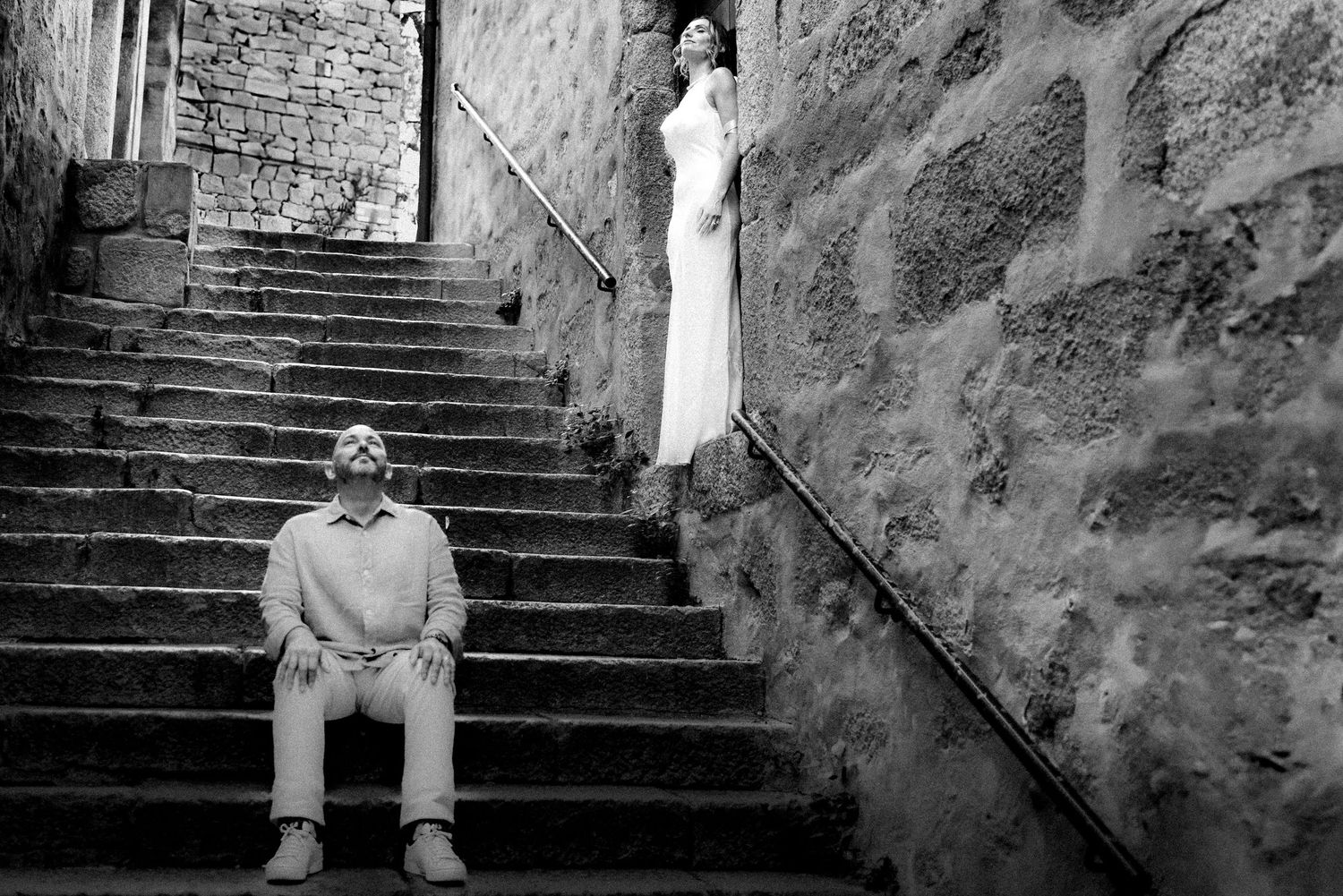 Artistic black and white shot of two people on weathered stone steps.