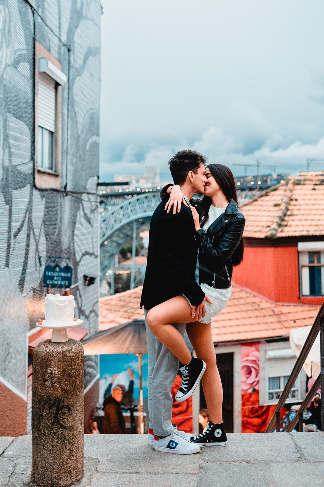 A casual photo session on wooden posts with orange rooftops in the background.