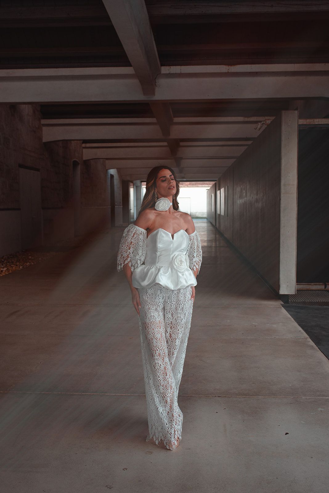 Contemporary bridal outfit with structured bodice and lace pants in industrial setting.