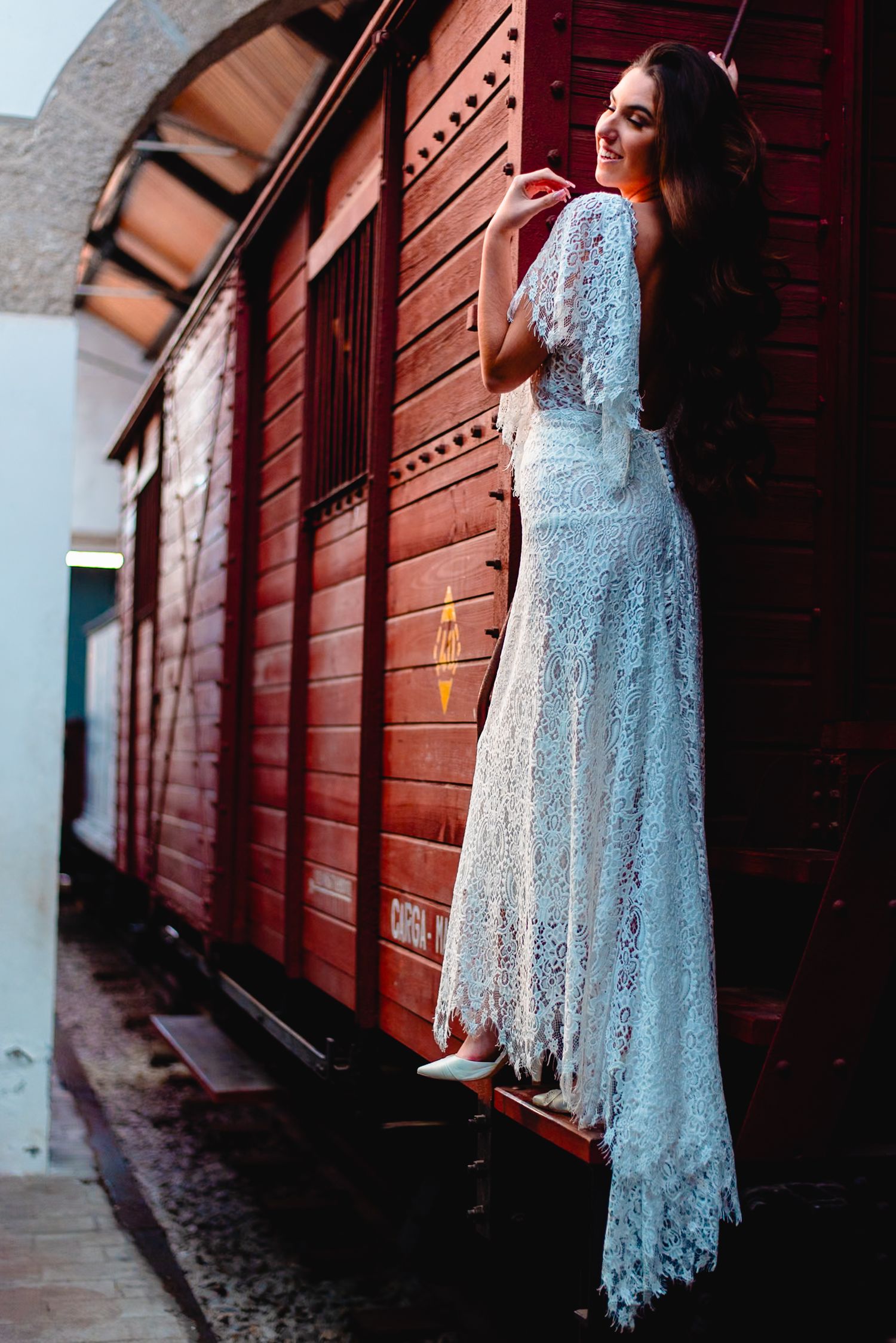 Ethereal blue lace dress captured in dramatic lighting against rustic red wooden walls.