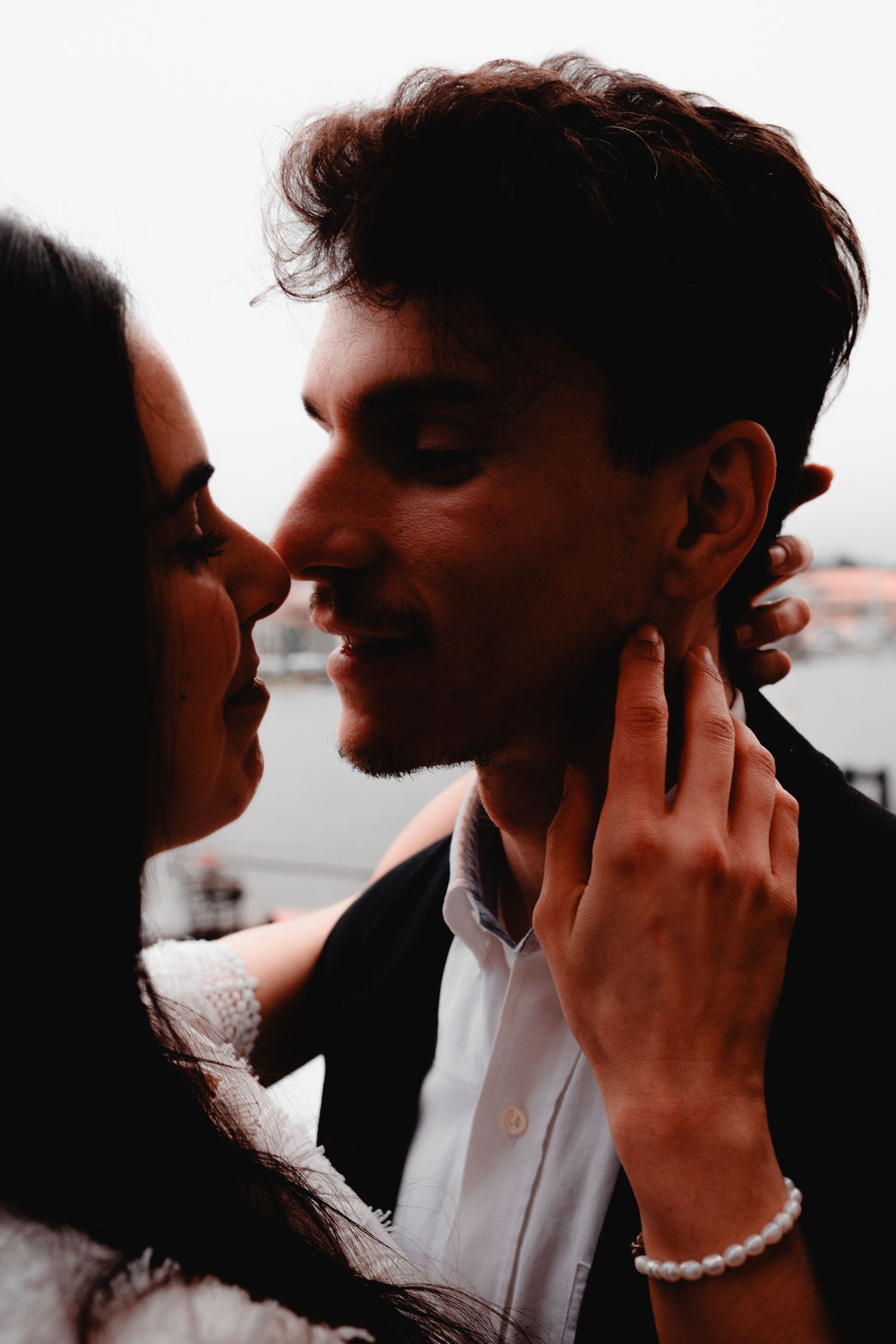 A romantic couple sharing an intimate moment, woman gently touching man's face, soft moody lighting outdoors.