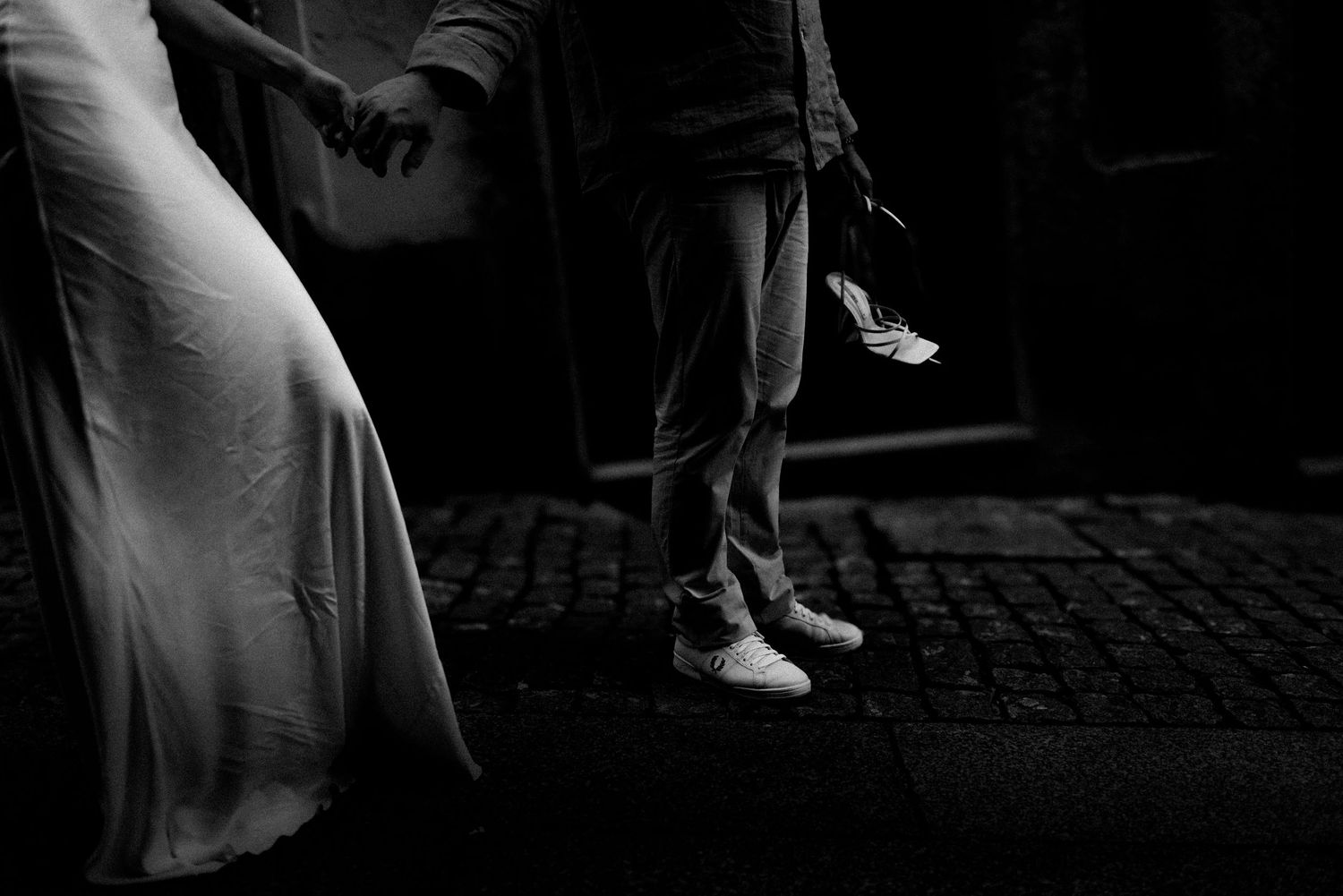 A couple embraces on rustic stone steps bathed in dramatic lighting and shadows.