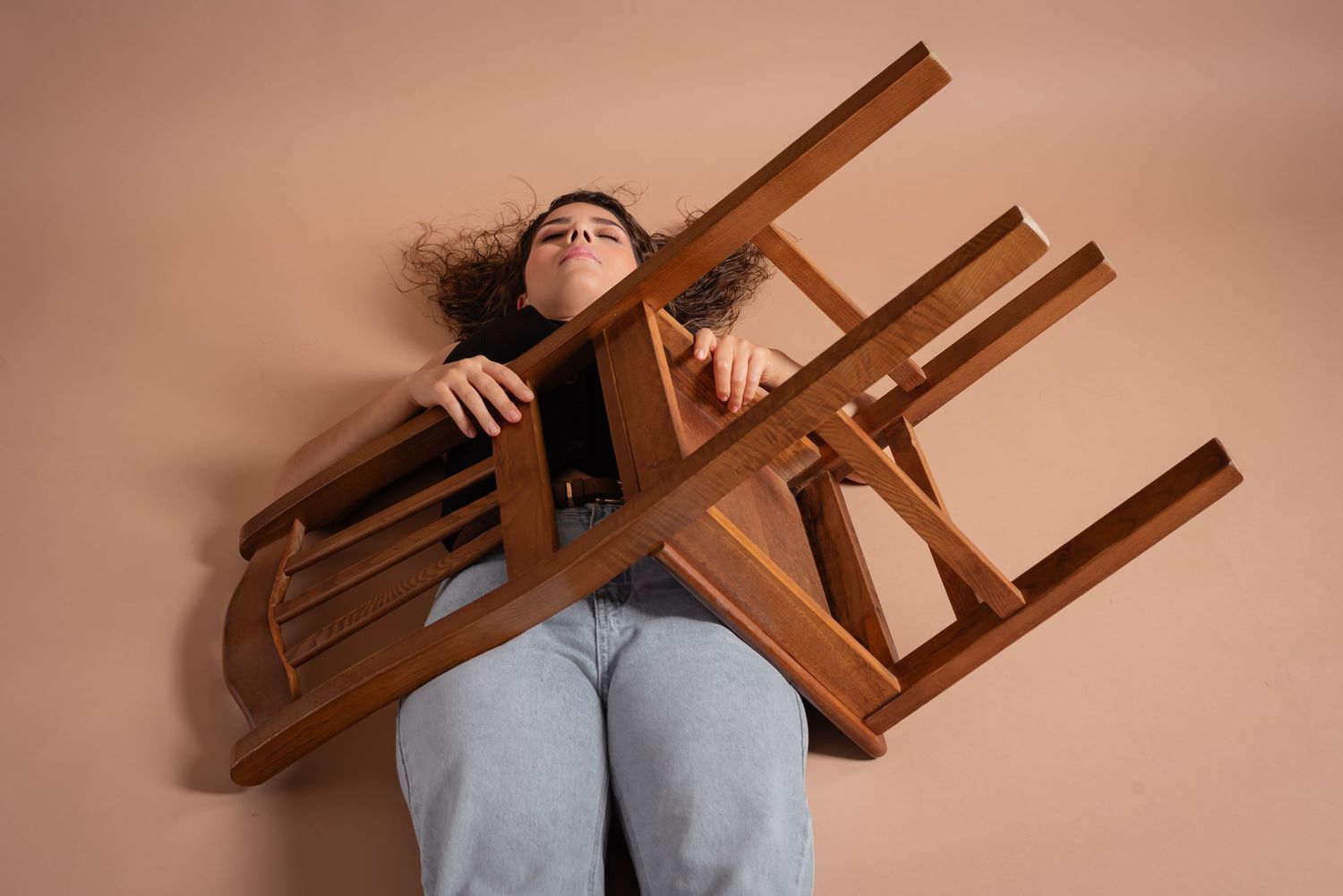 Dynamic pose with multiple wooden chairs creating interesting geometric shapes.