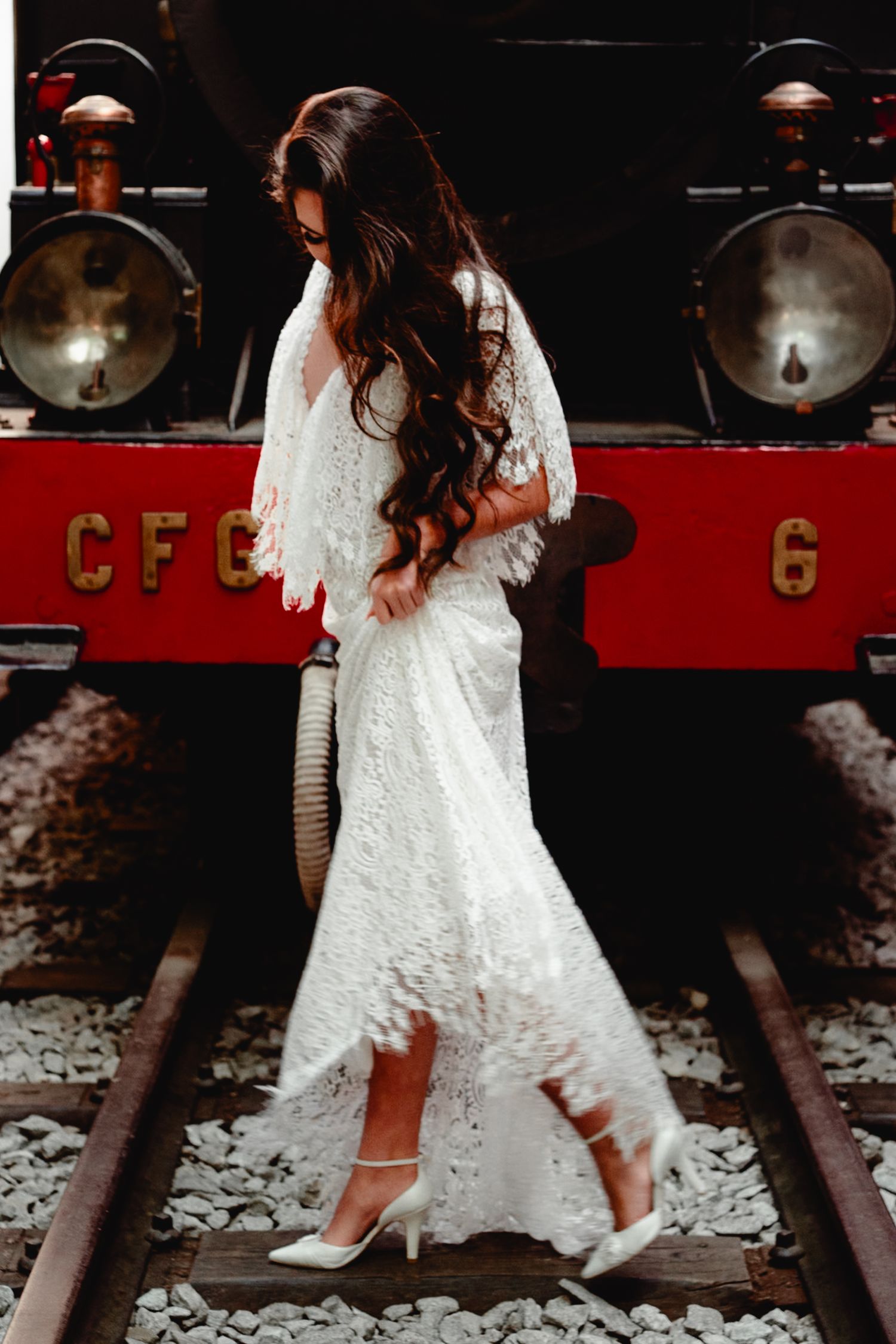 Elegant white lace wedding dress detail shot against vintage red train background.