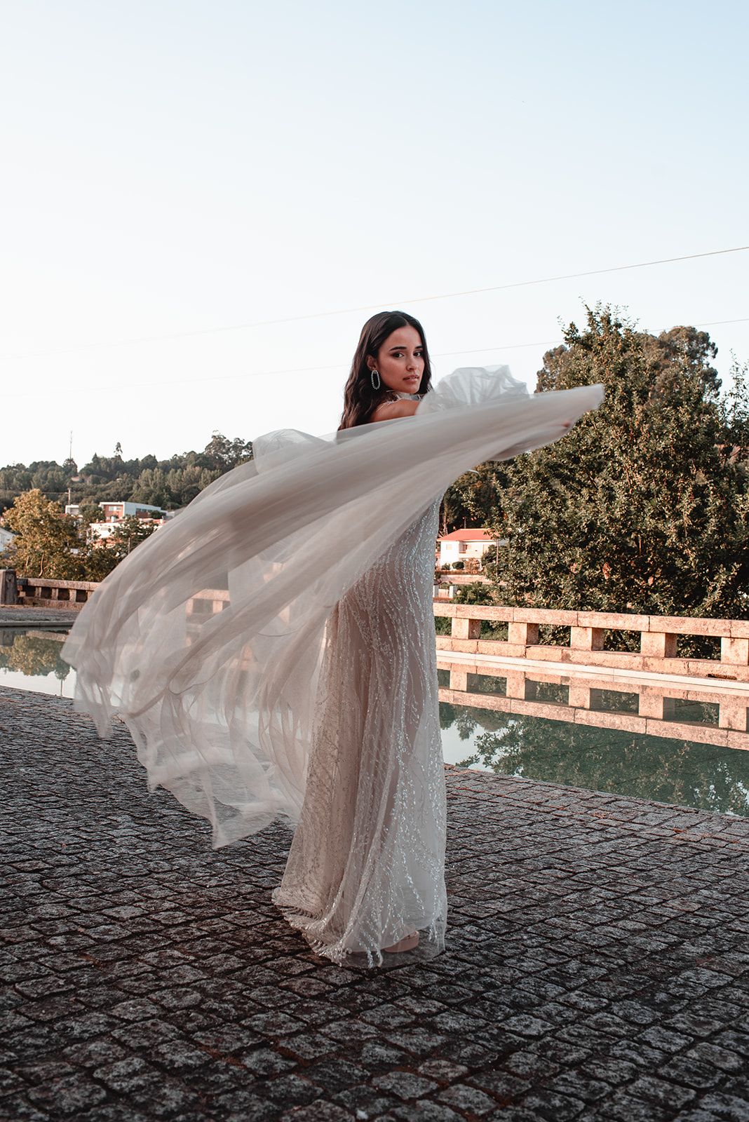 Romantic bridal portrait with flowing veil caught in motion against an urban backdrop.