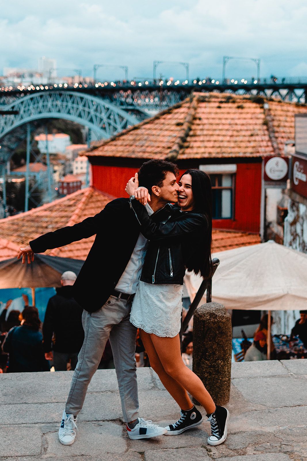 A couple dancing together in a playful series of poses on an urban rooftop with terracotta tiles.