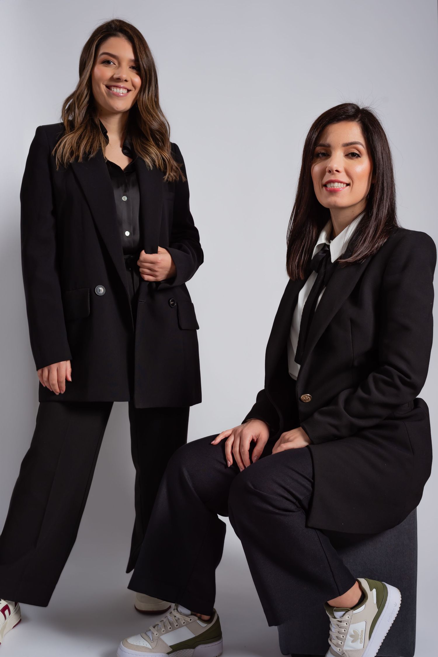Two people in matching black business suits posing for professional studio photo.