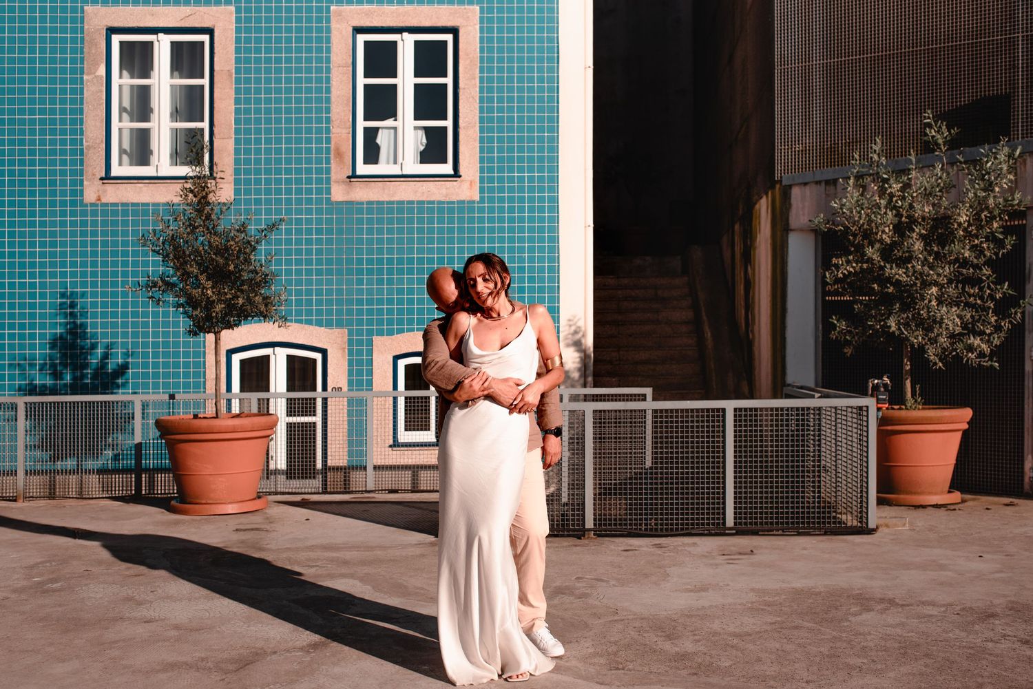Couple poses in front of traditional Portuguese blue-tiled building facade.