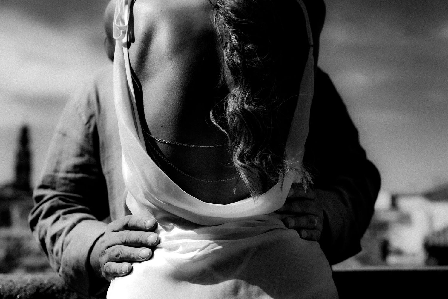 Black and white photo of a couple embracing, woman in backless dress with man's hand on her waist.