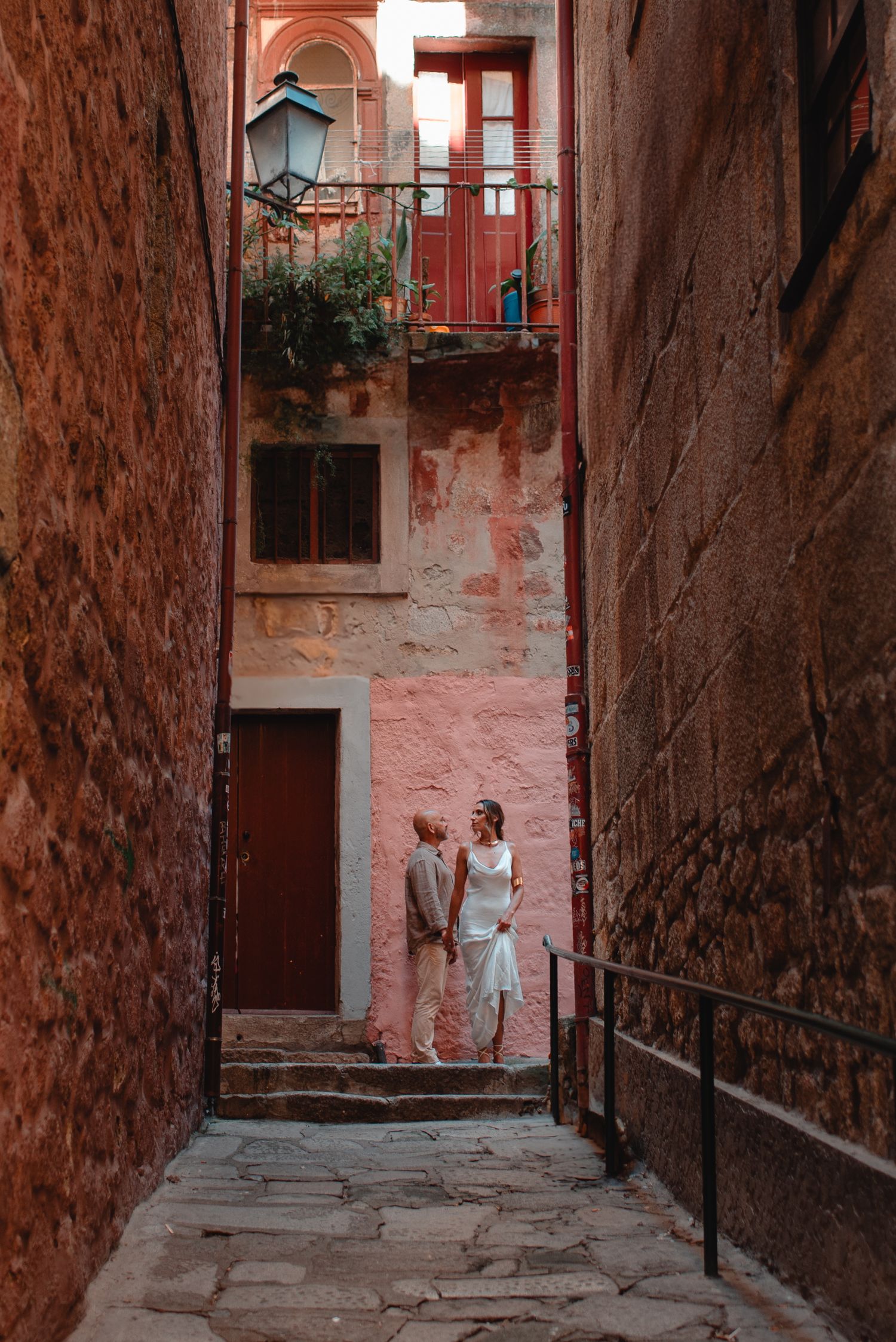Pink-tinted stone alleyway with stairs and rustic architecture creates atmospheric scene.