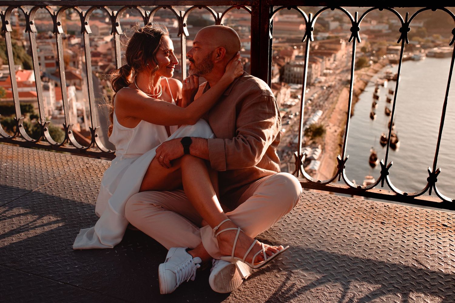 Romantic couple shares intimate moments at sunset along an ornate railing.