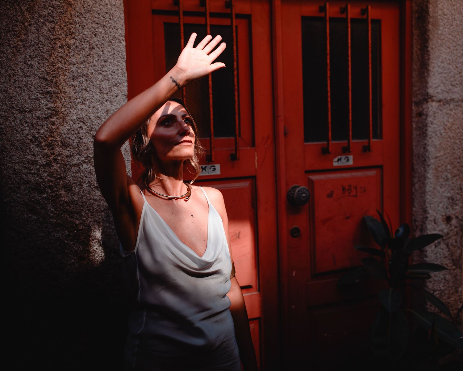 Dramatic shadows play across a vintage red doorway as a couple shares a romantic moment.
