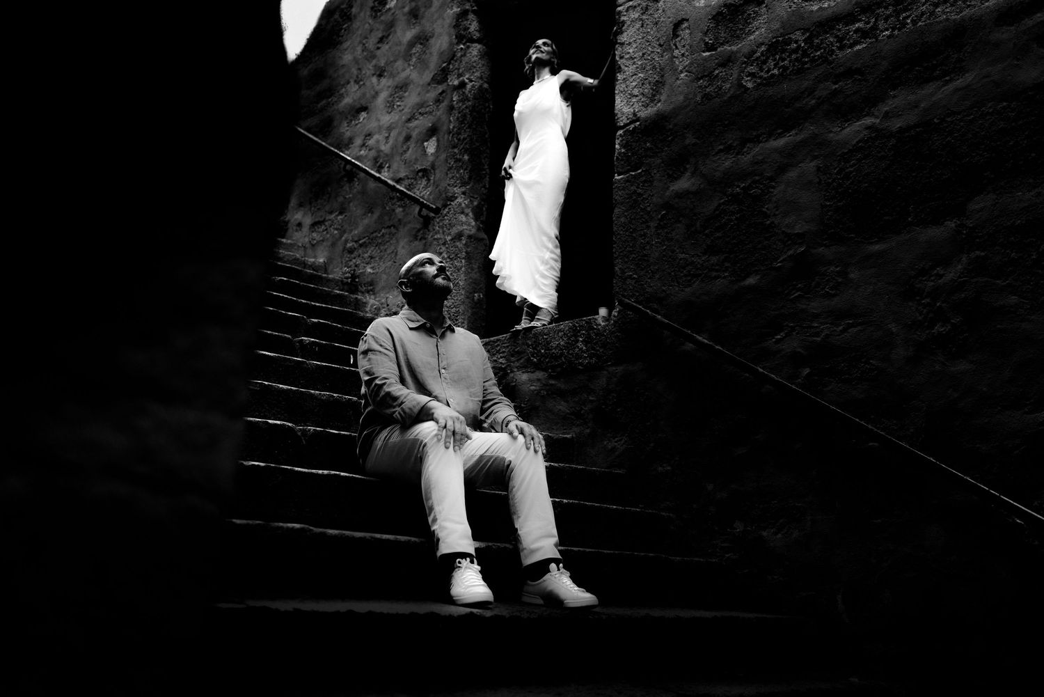 Black and white photo of couple on stone staircase creating dramatic silhouette.