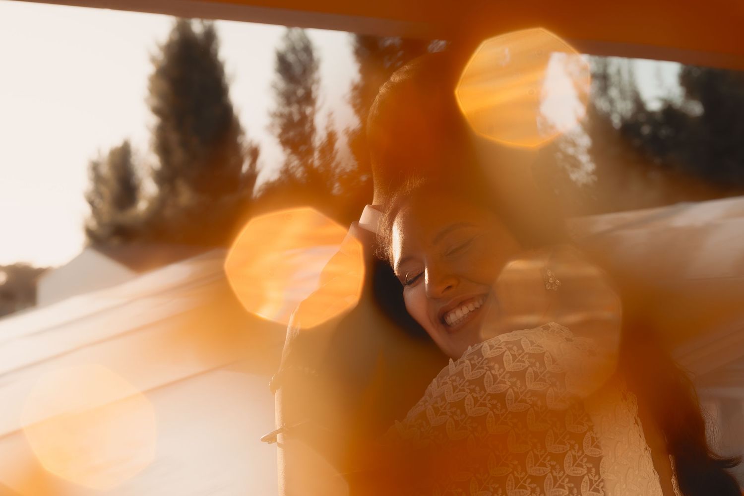 Romantic couple embracing in warm golden sunlight with dreamy lens flare bokeh effect outdoors.