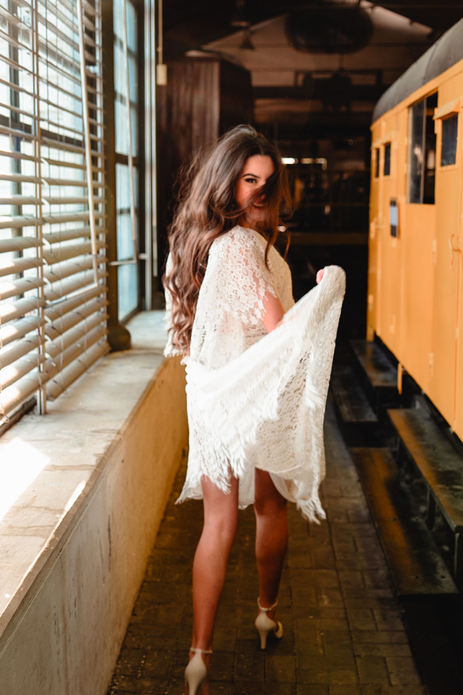 White lace dress flows gracefully in vintage train station hallway.