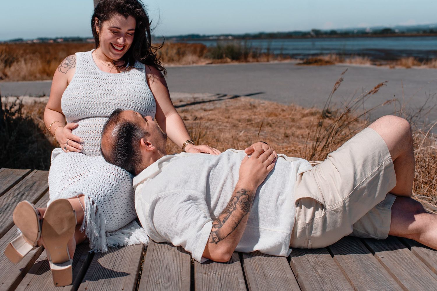 Candid moment of couple relaxing on wooden deck by waterfront.