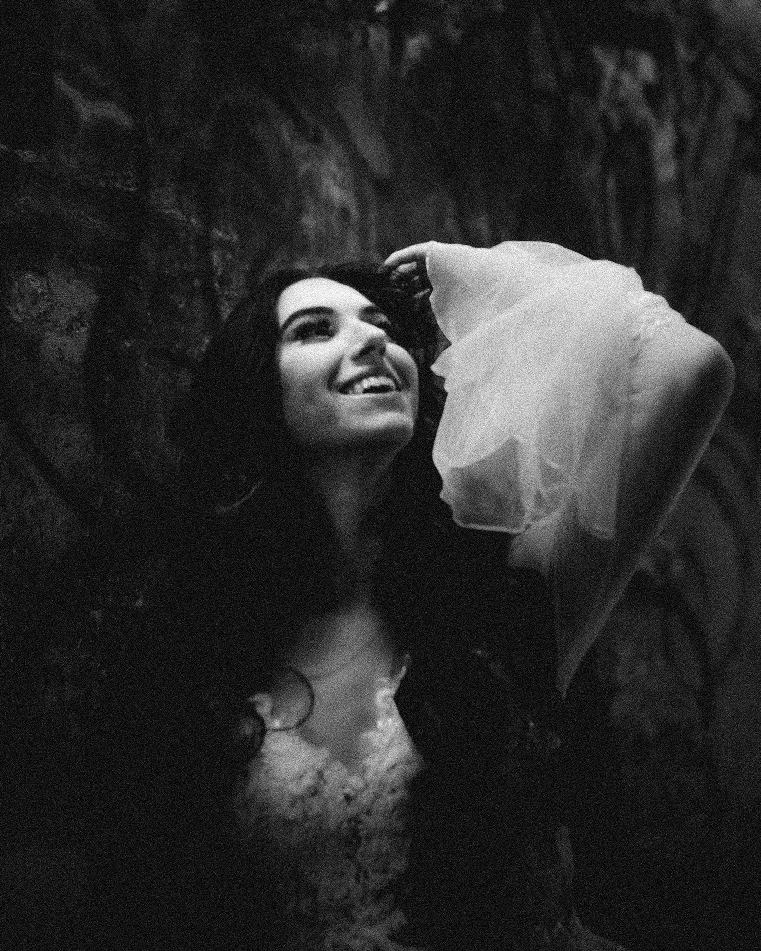Wedding dress portrait with ethereal veil against dark textured background.