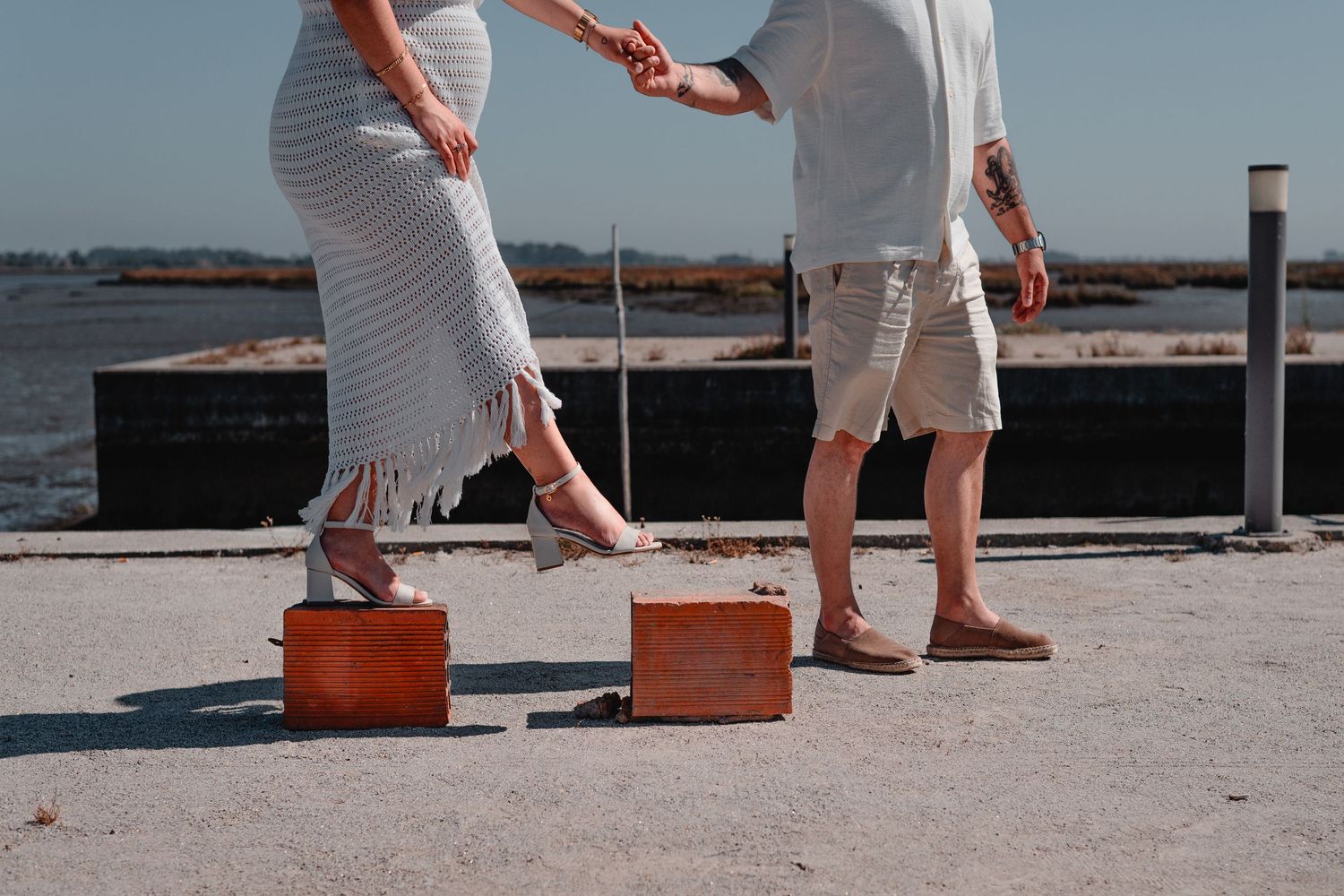 People walking on concrete pier holding red objects near the water.