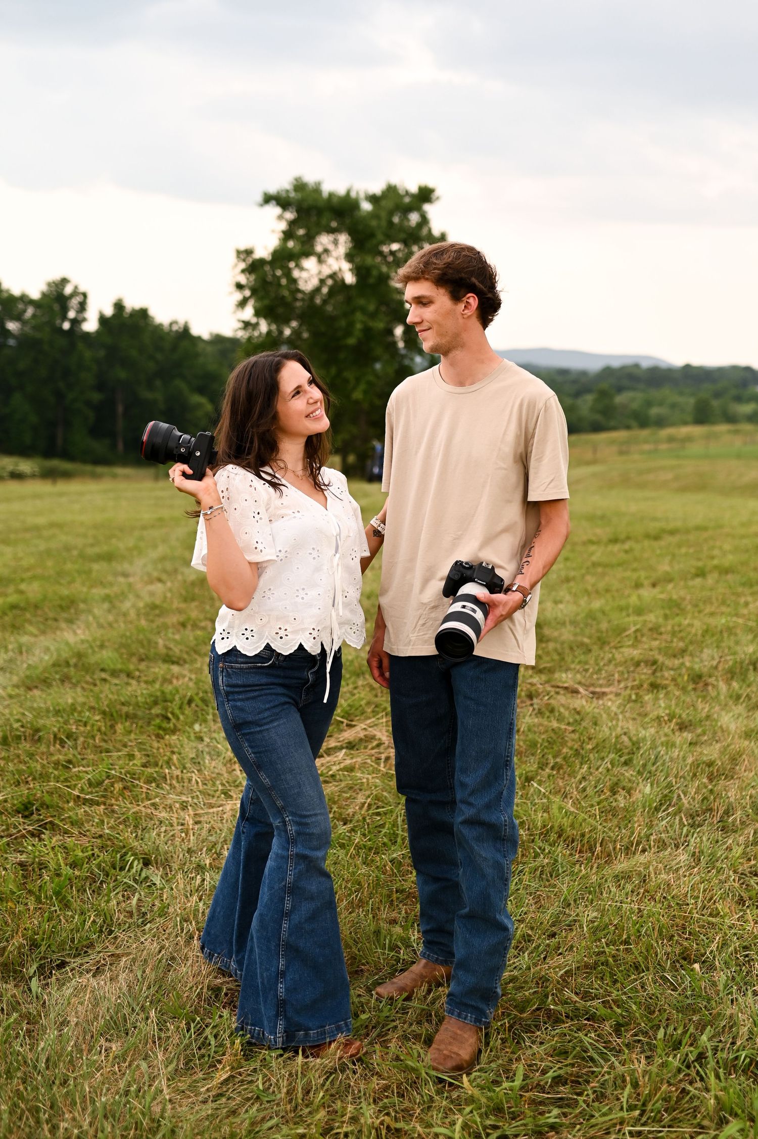 Couple smiling and holding hands in an open field during a golden hour lifestyle session in North Carolina