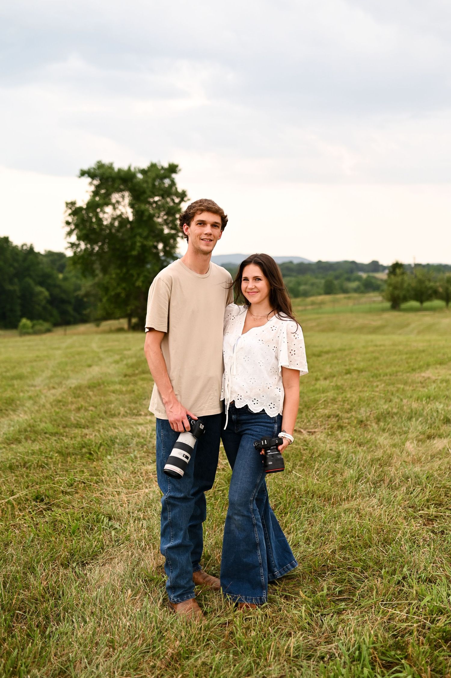 Couple standing together in a wide-open field, branding shoot for Still Sunday Media photography duo