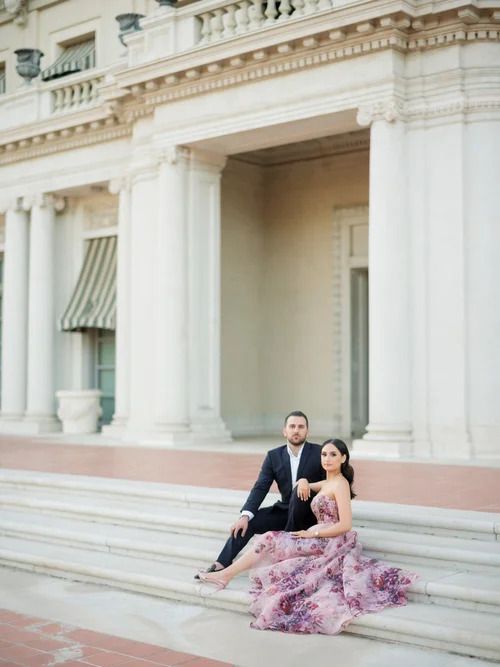 Couple lounging on classic white stone architecture with elegant columns.