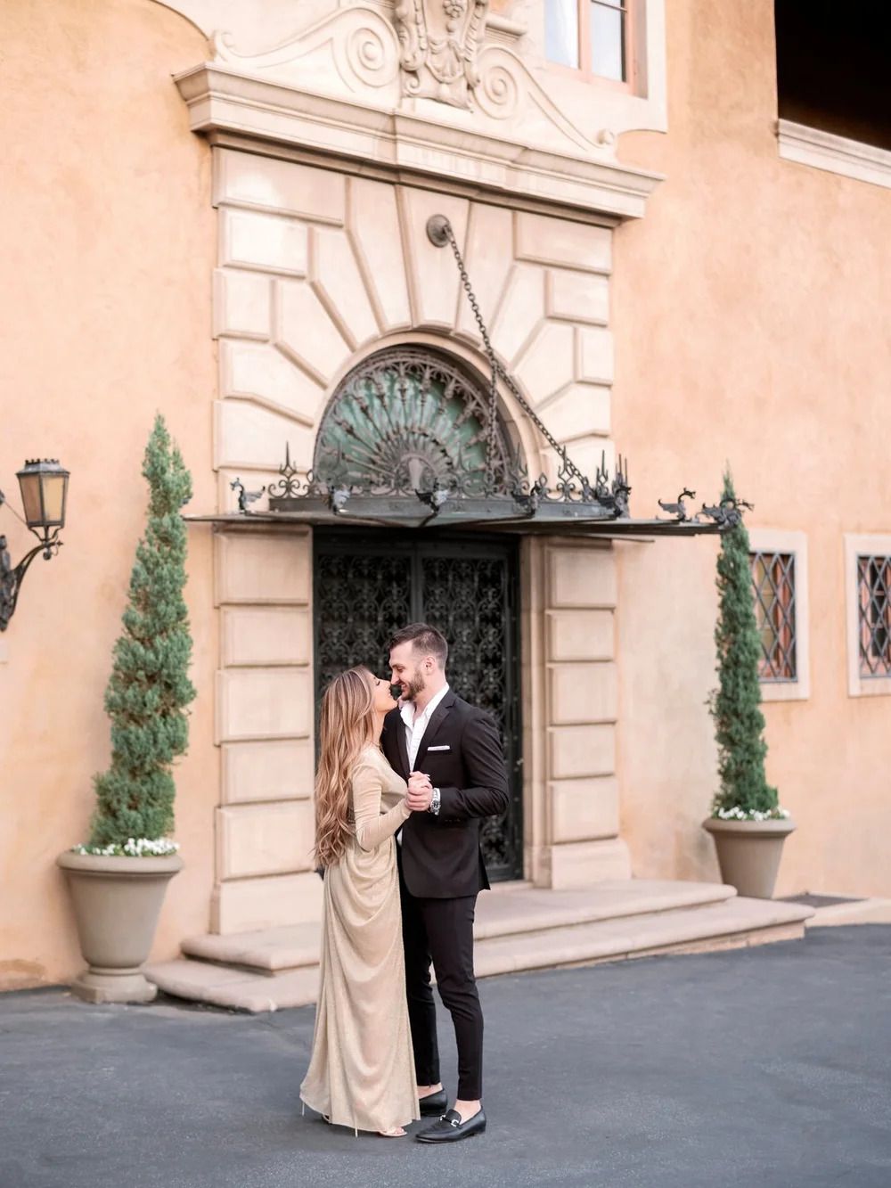 Elegant scene at Mediterranean building entrance with ornate ironwork and cypress trees.