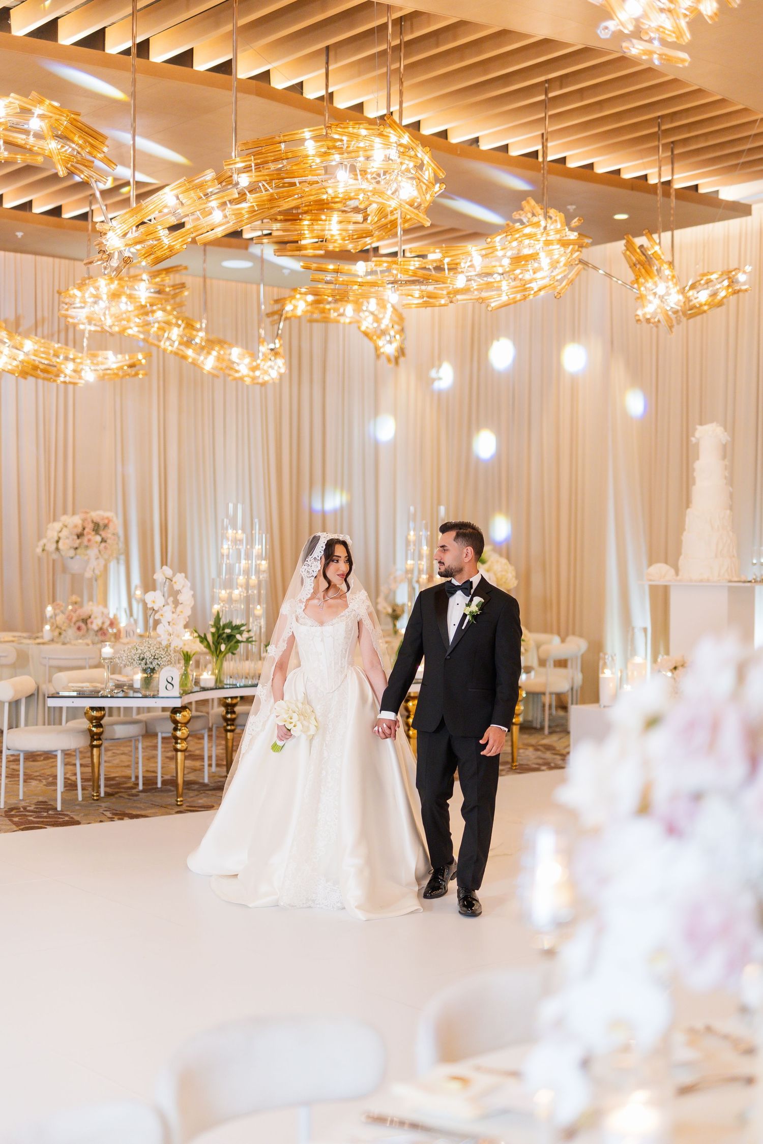 Elegant wedding venue with white drapes and golden starburst chandeliers creates a romantic atmosphere.