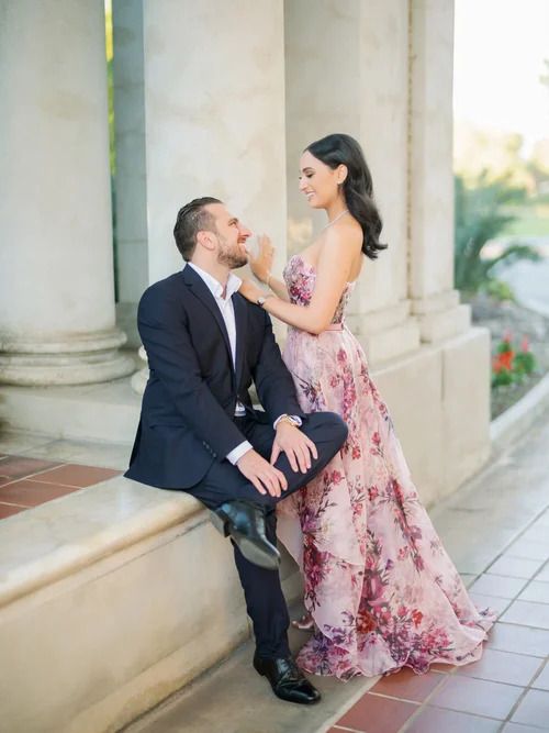 Couple in formal attire shares romantic moments along a columned walkway at sunset.