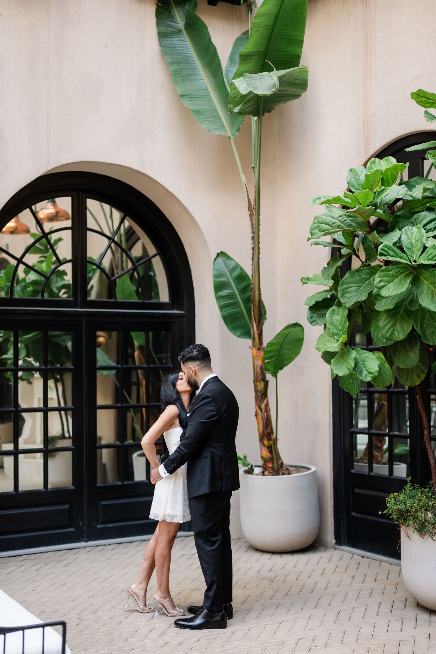 Romantic courtyard photoshoot with black arched windows and tropical greenery.