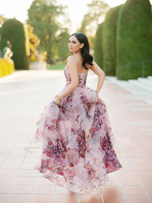 Flowing pink floral dress twirling against classic architecture and garden backdrop.
