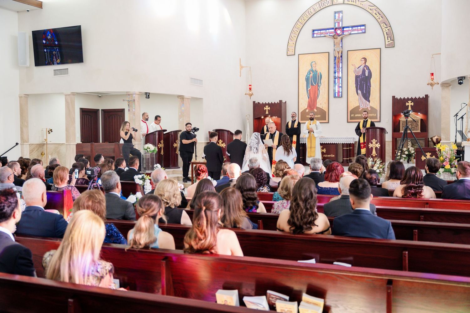 Wide view of a traditional church interior during a wedding ceremony with religious icons.