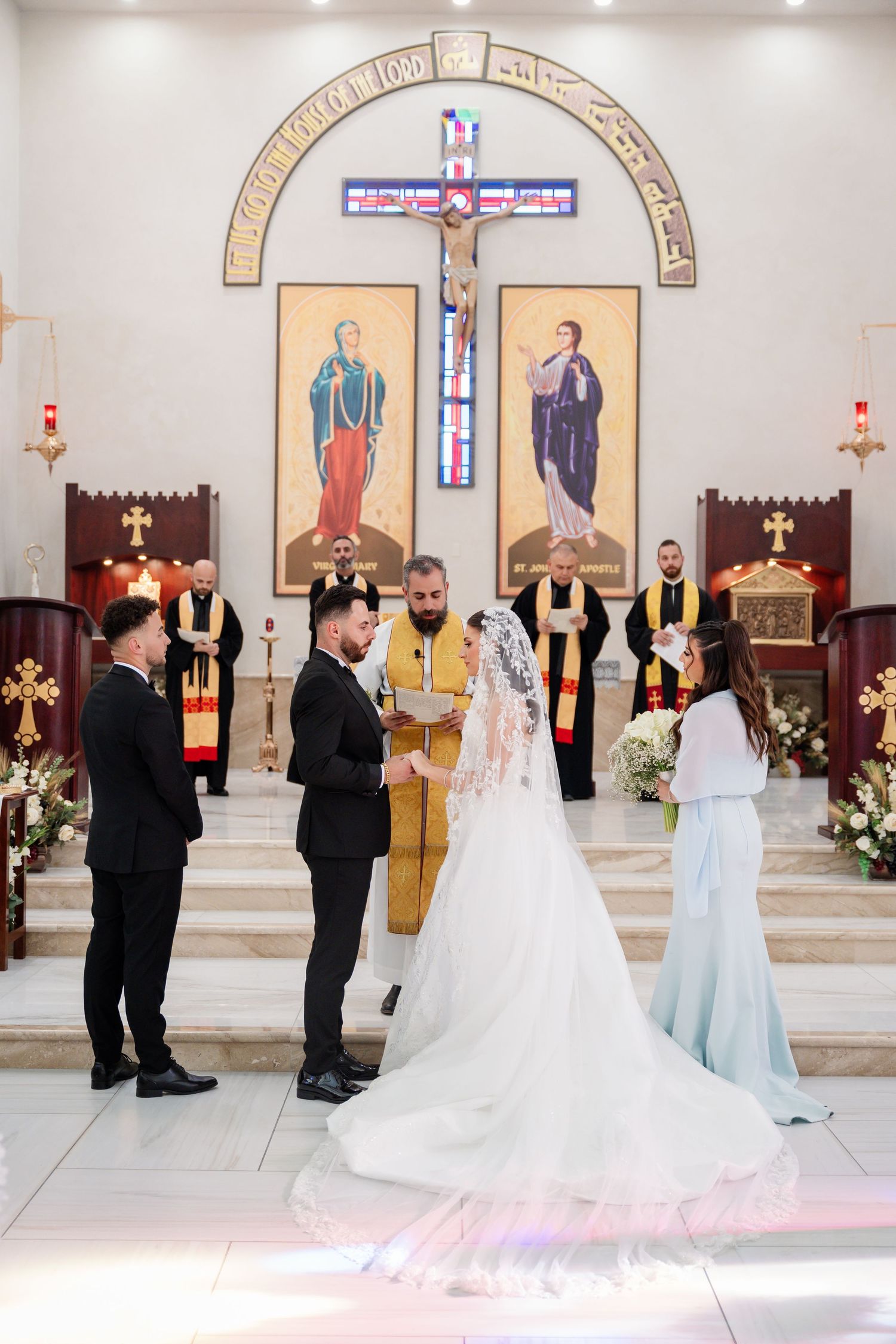 Wedding ceremony in a church with religious icons and stained glass windows.
