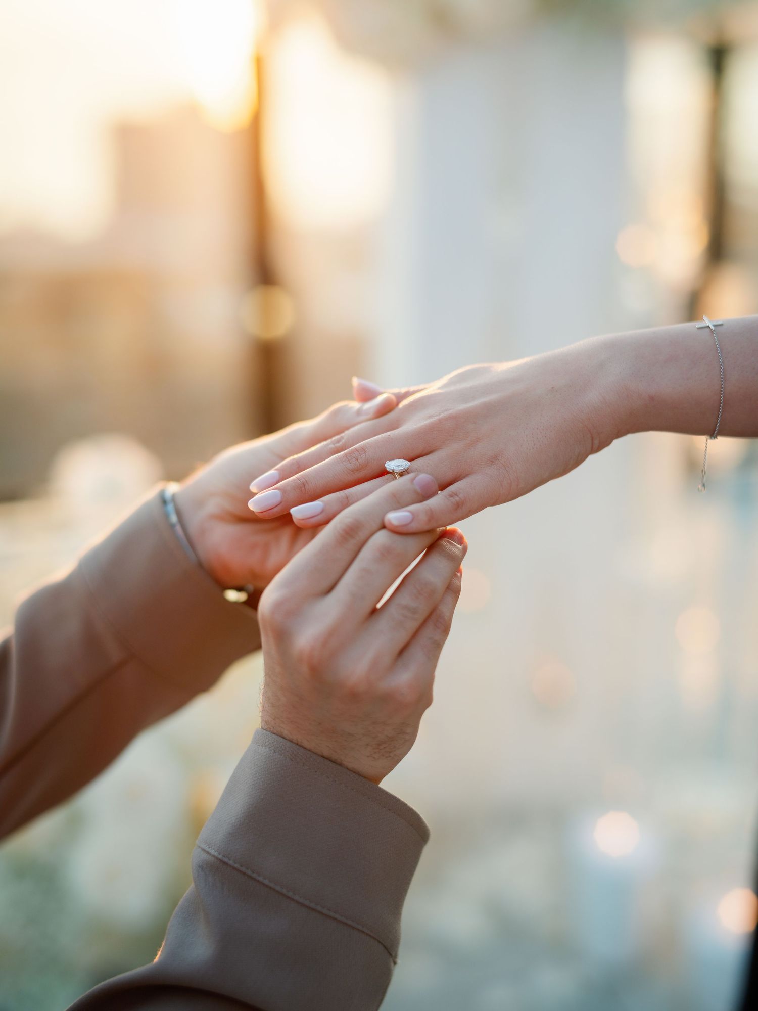 Close-up of hands exchanging rings during a romantic sunset proposal.