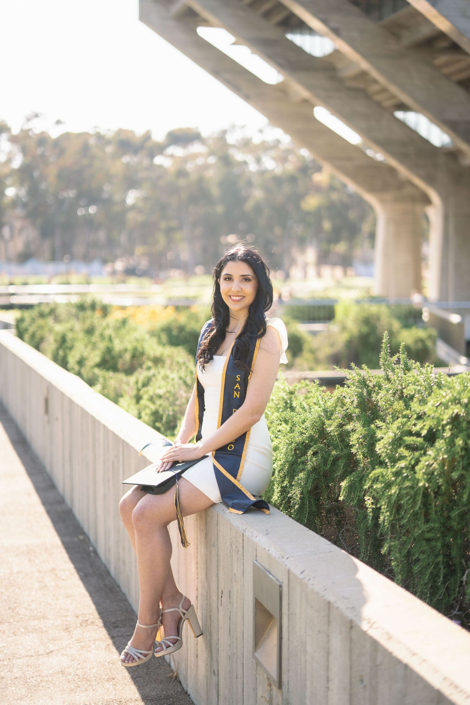 A series of outdoor portrait photos taken on a concrete ledge with greenery in the background.
