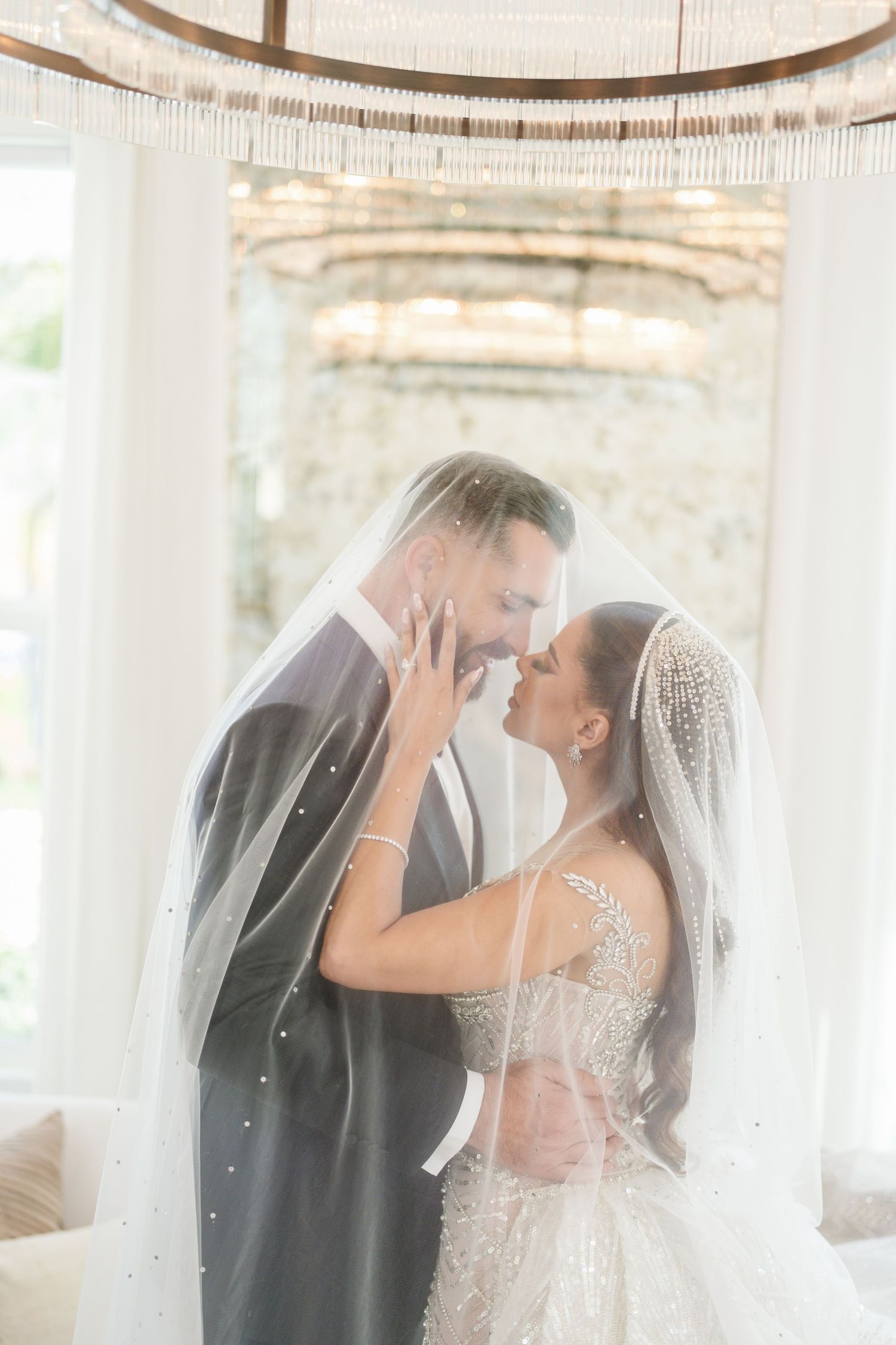 Ethereal wedding moment captured in a light-filled room with white curtains and elegant decor.