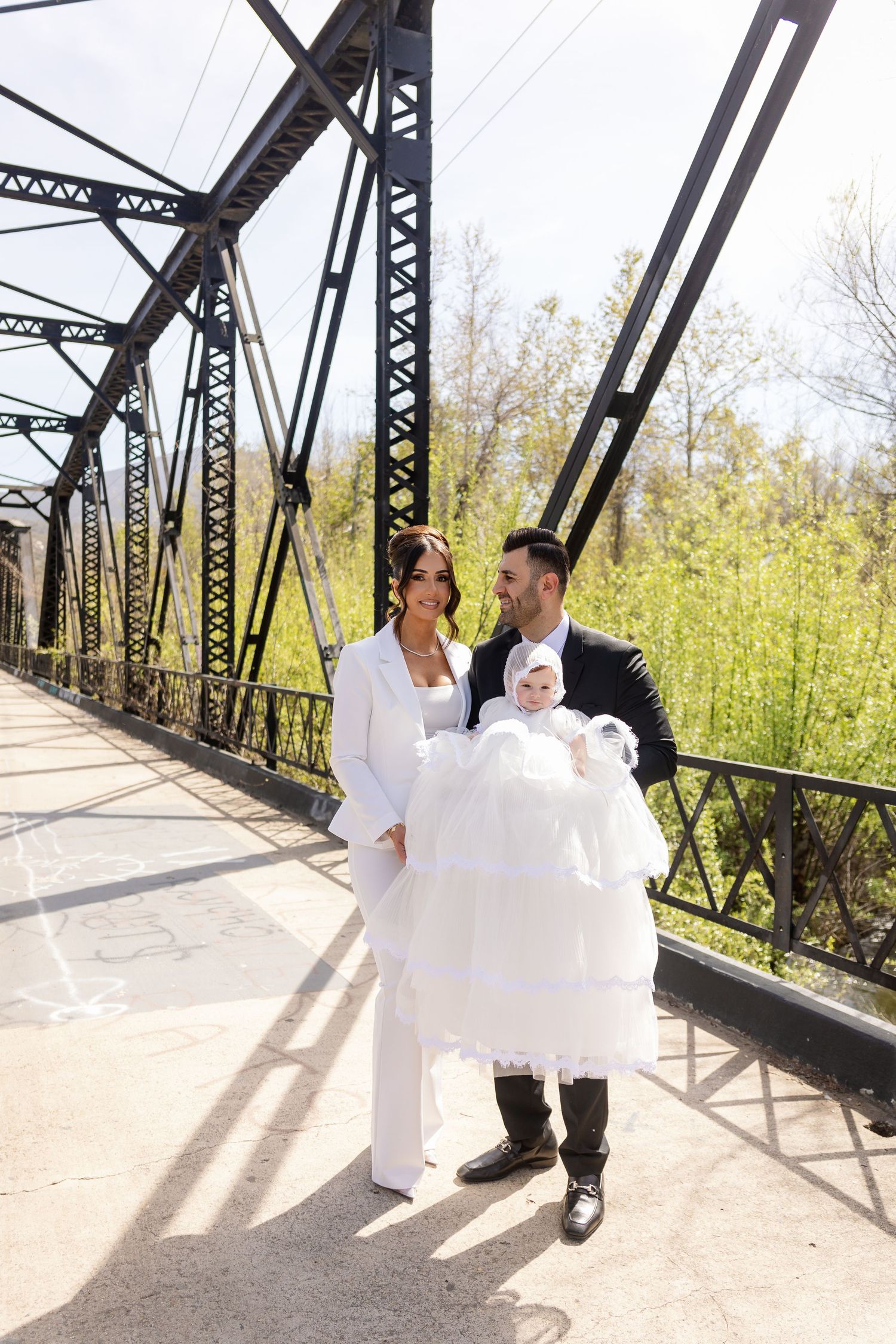 A series of romantic wedding photos showing a couple in formal attire posing on a rustic steel bridge in natural sunlight.