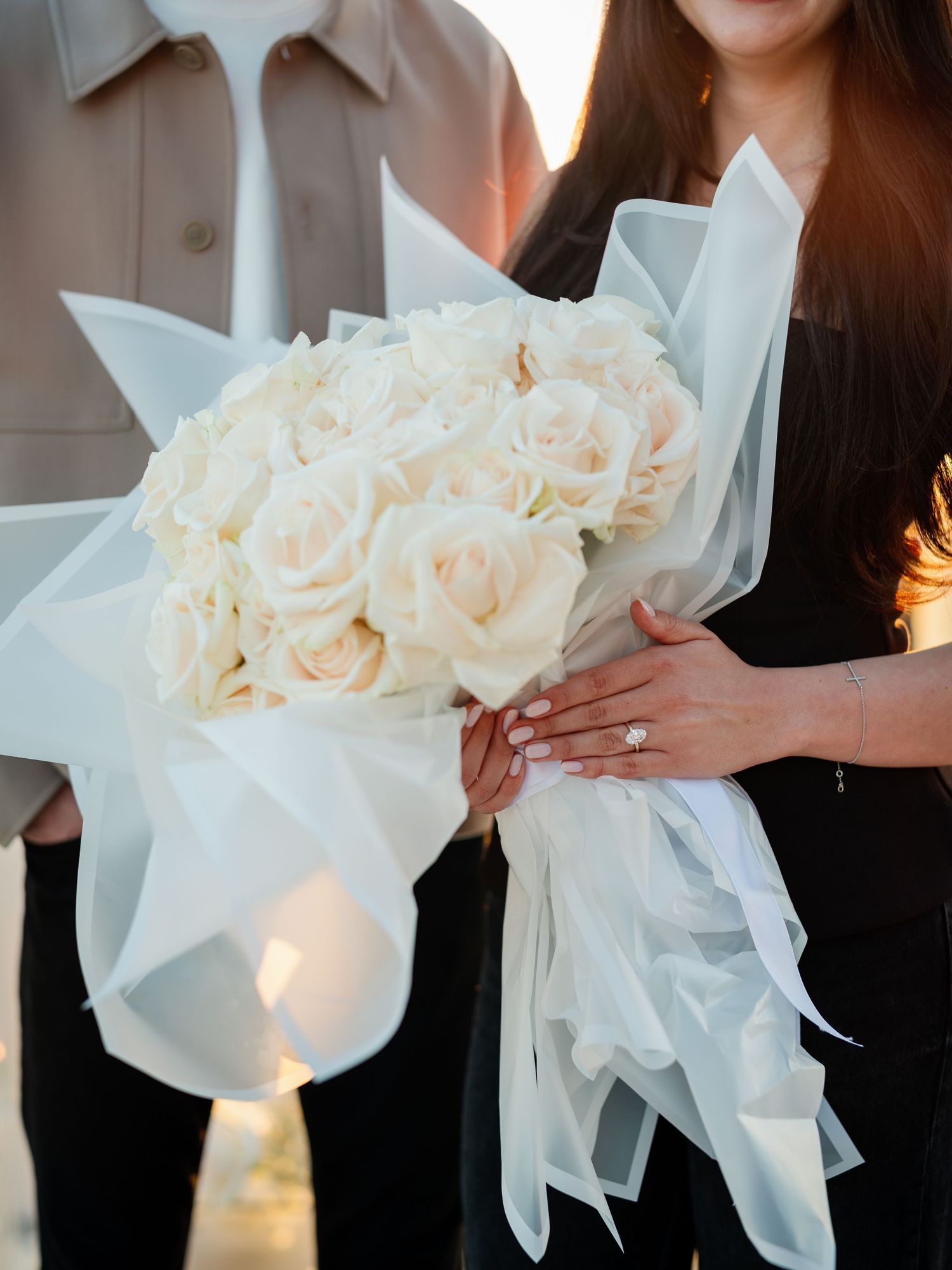 Elegant white rose bouquets wrapped in silk fabric captured in golden hour light.