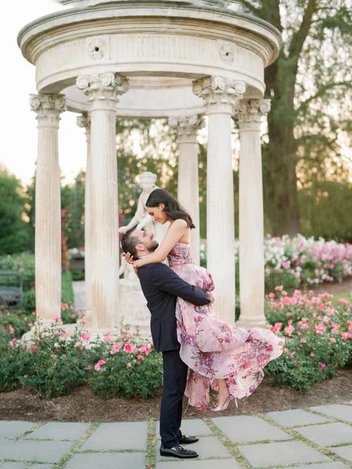 Romantic dance poses captured in a garden gazebo surrounded by pink flowers.