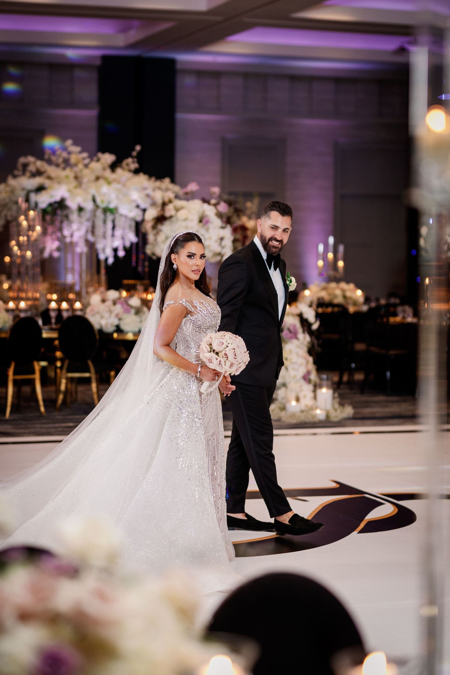 Elegant wedding reception with purple lighting and white floral decorations.