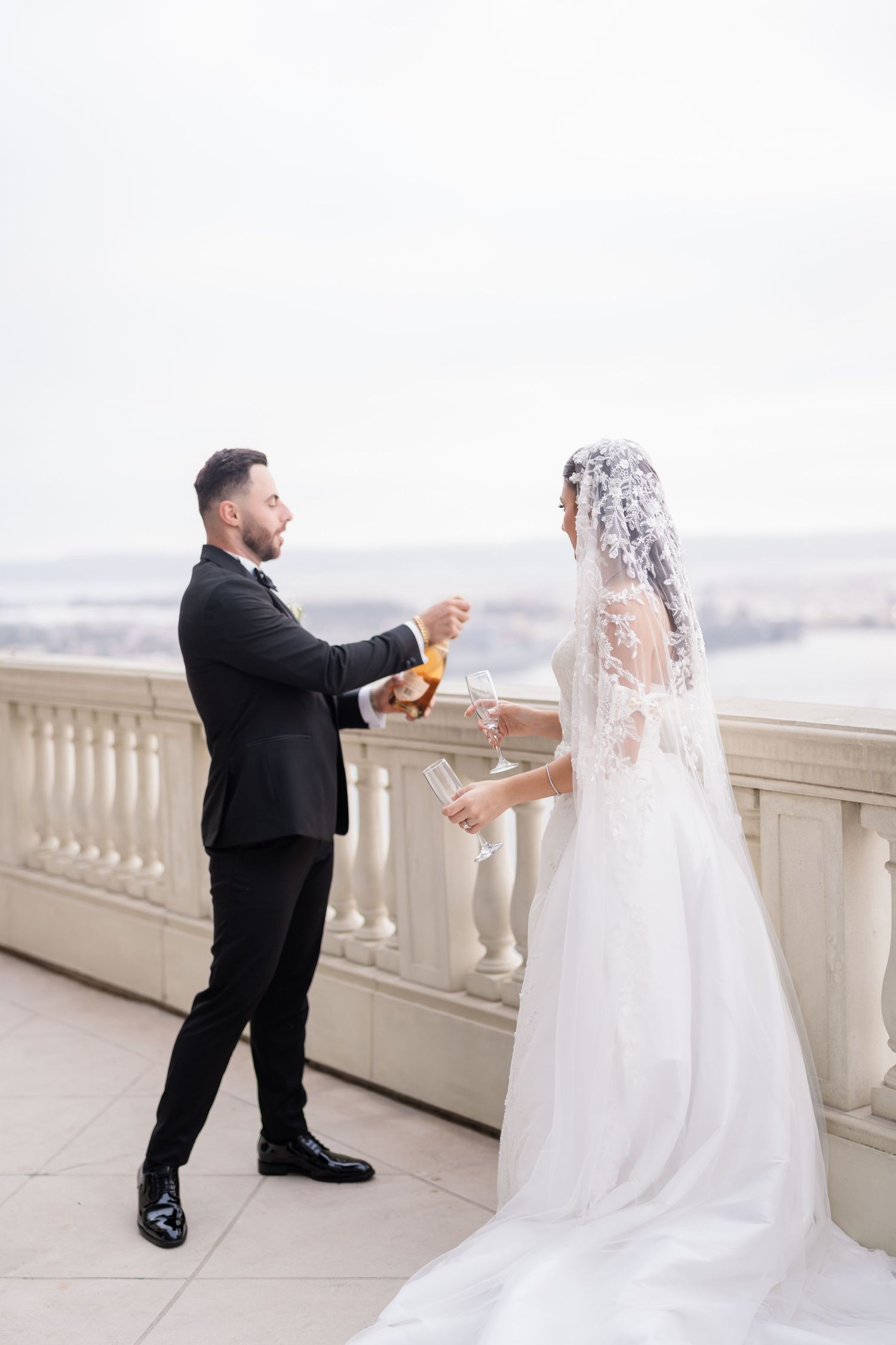 A couple shares a special moment during a wedding proposal on an elegant white balcony.