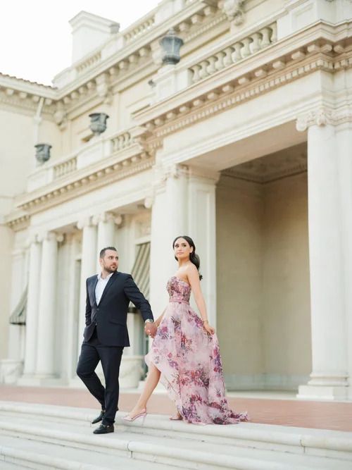 Elegant couple posing against white classical architecture with ornate details.