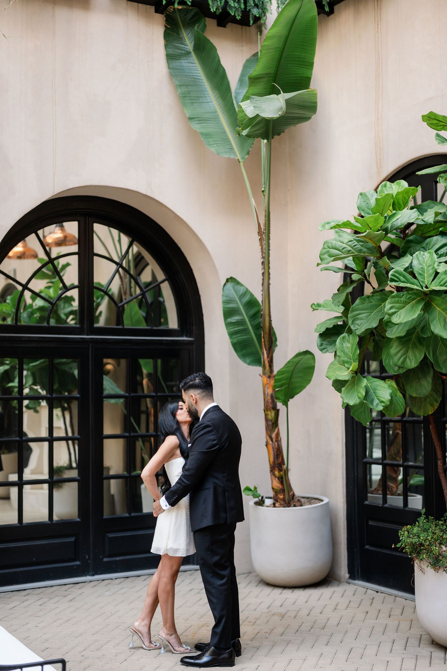 Romantic courtyard setting with arched windows and tropical plants in white planters.